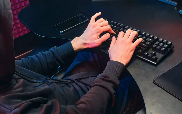 Personne devant un écran, mains sur le clavier
