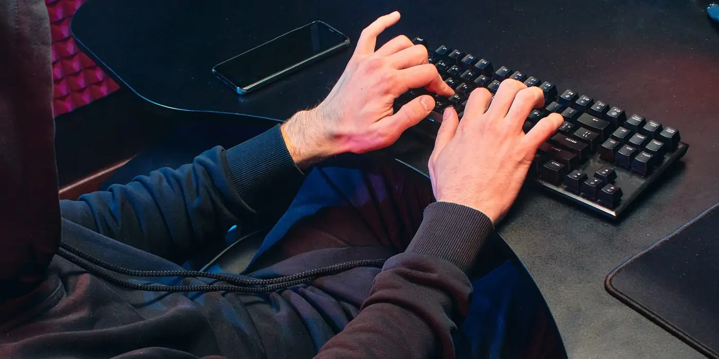 Personne devant un écran, mains sur le clavier
